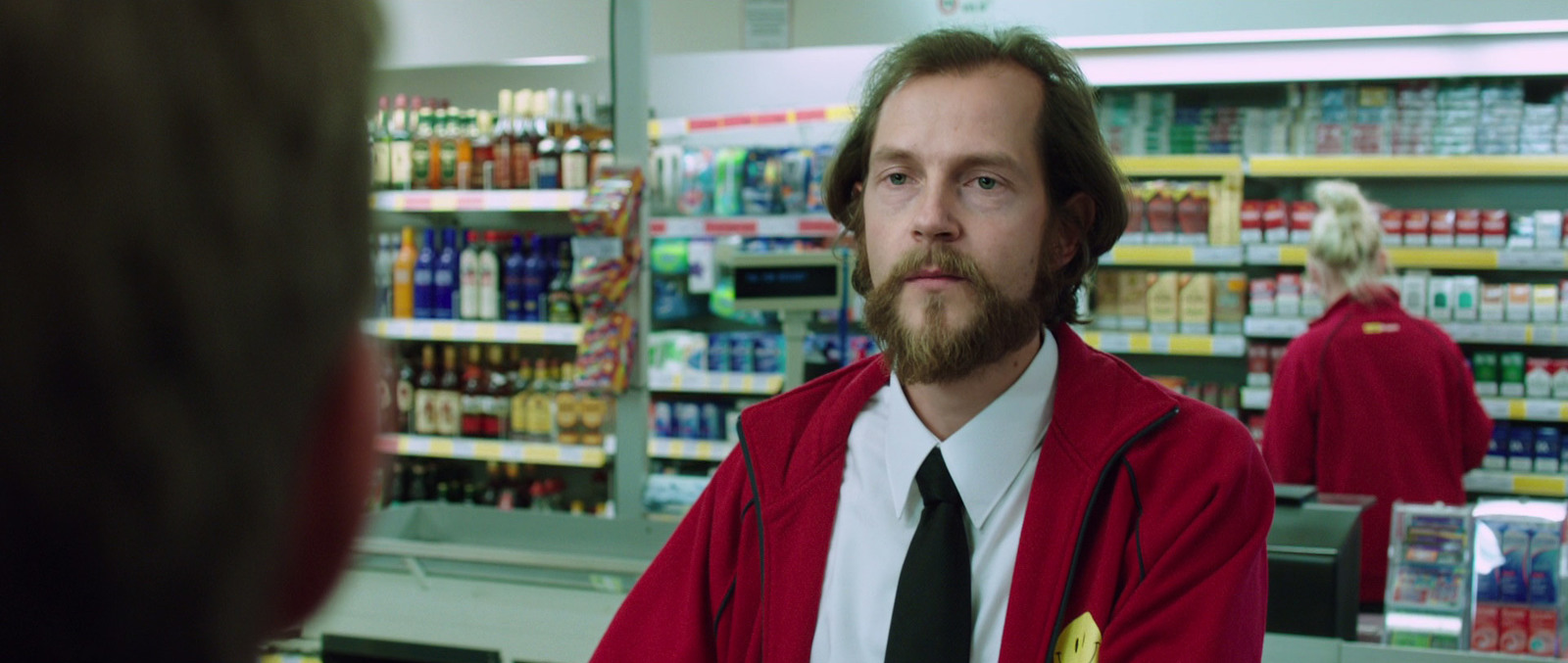 a man in a red jacket and tie standing in a store