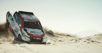 a red and white truck driving through sand dunes