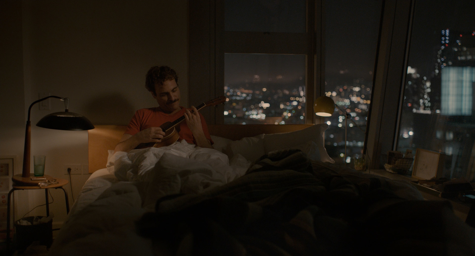 a man sitting on a bed playing a guitar