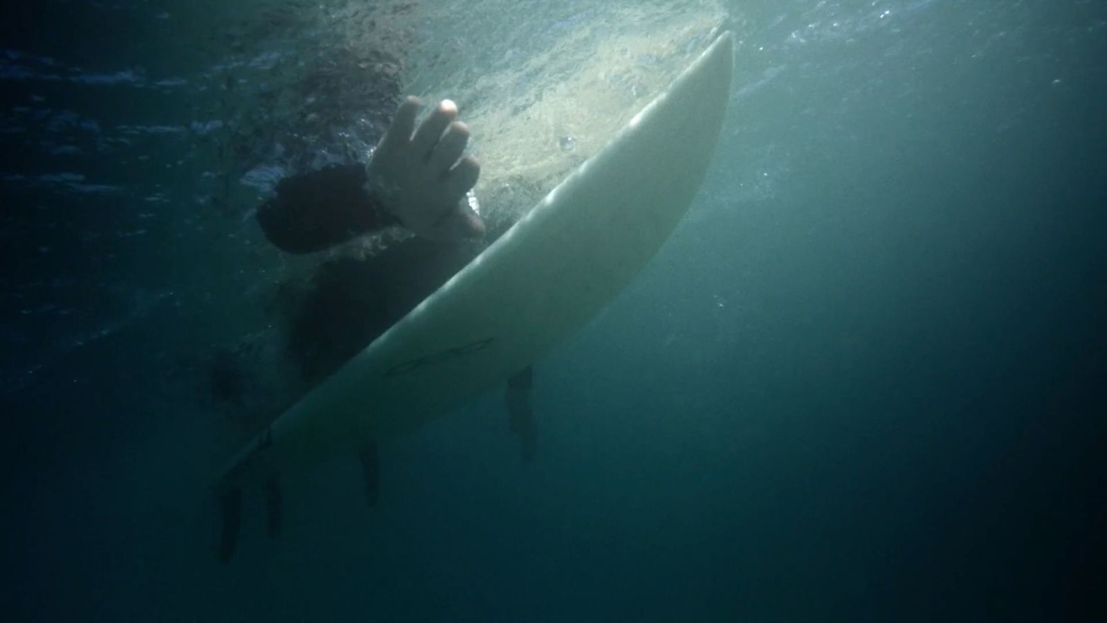 a person holding a surfboard under the water