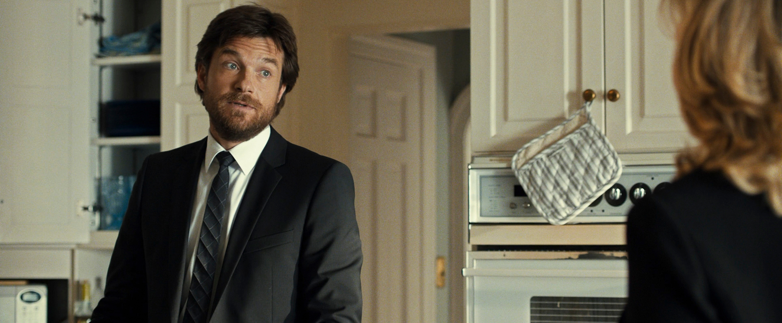 a man in a suit and tie standing in a kitchen