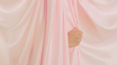 a person's hand peeking through a pink curtain