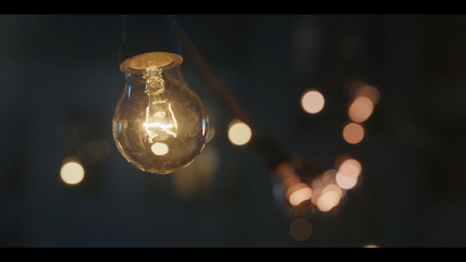 a light bulb hanging from a string with lights in the background