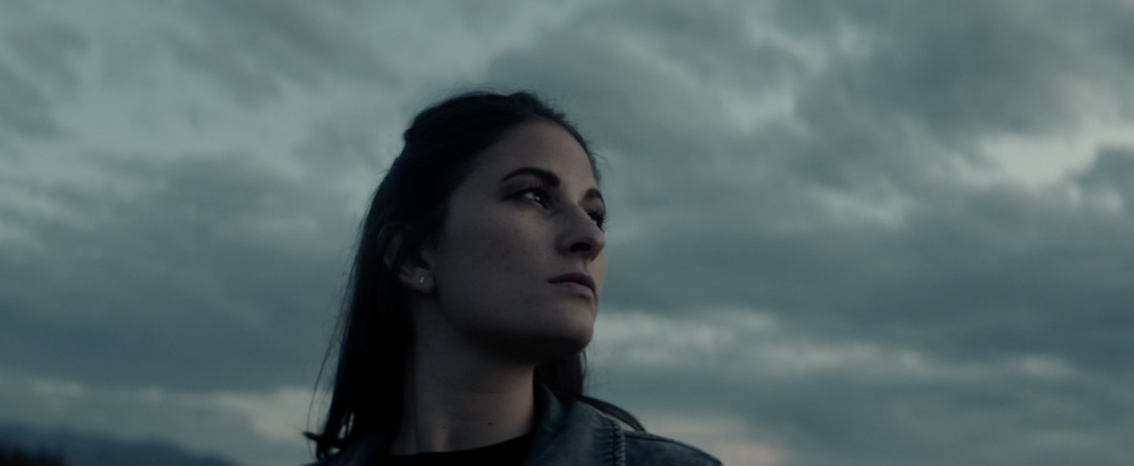 a woman standing in front of a cloudy sky