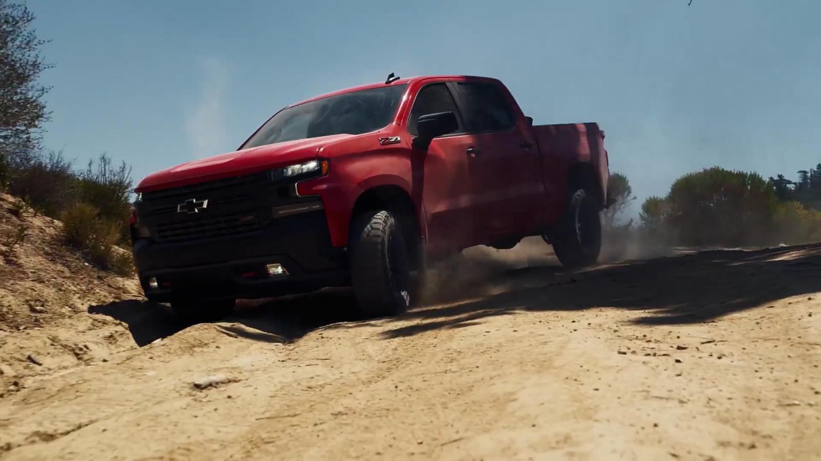 a red truck driving down a dirt road