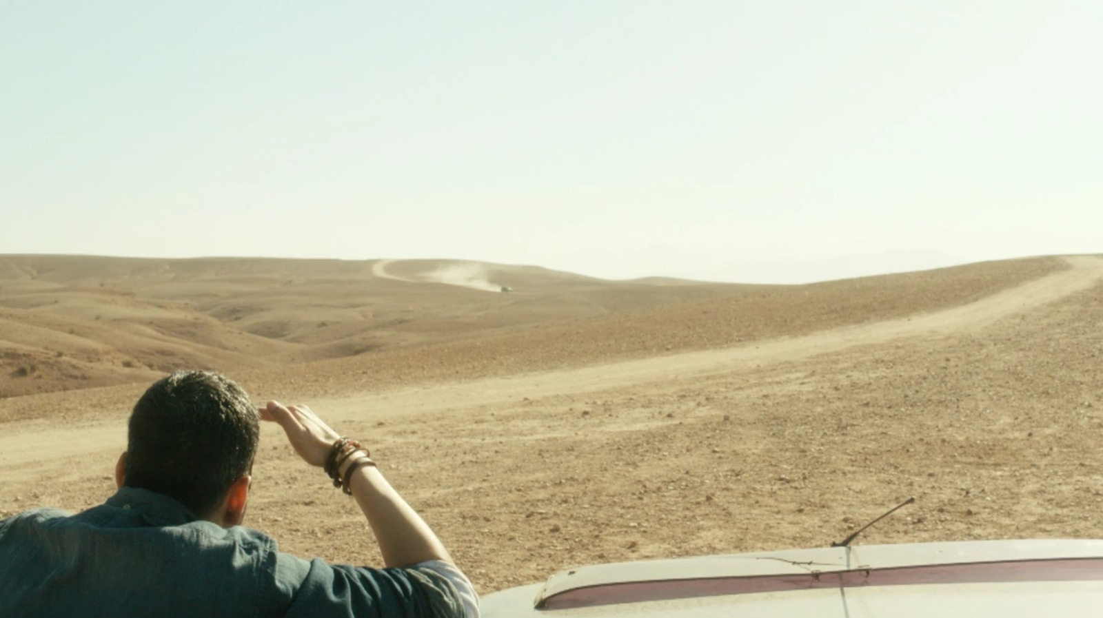 a man standing next to a white car in the desert