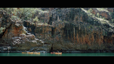 a group of people in canoes in front of a rocky cliff