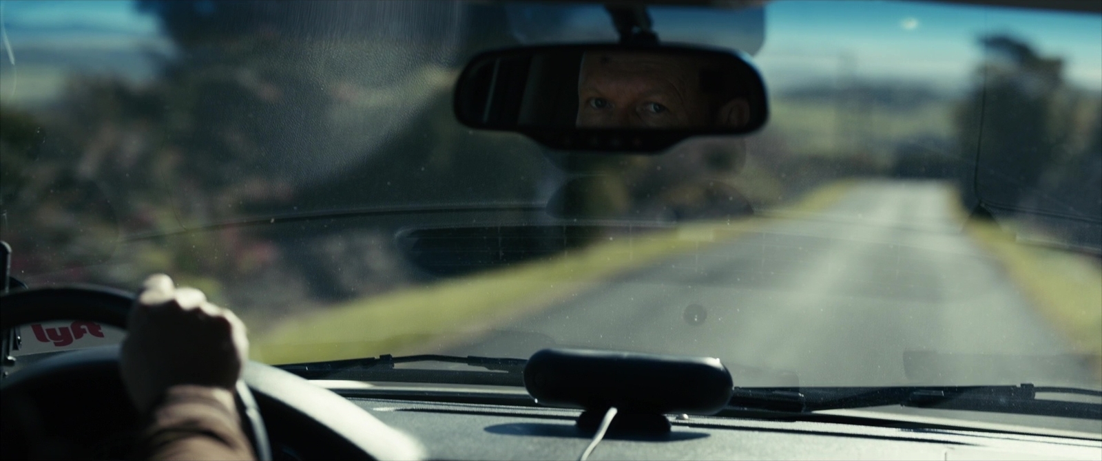 a man driving a car down a rural road