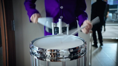 a woman in a purple jacket is playing a drum