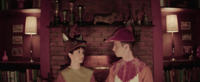 a man and a woman wearing costumes in front of a fireplace