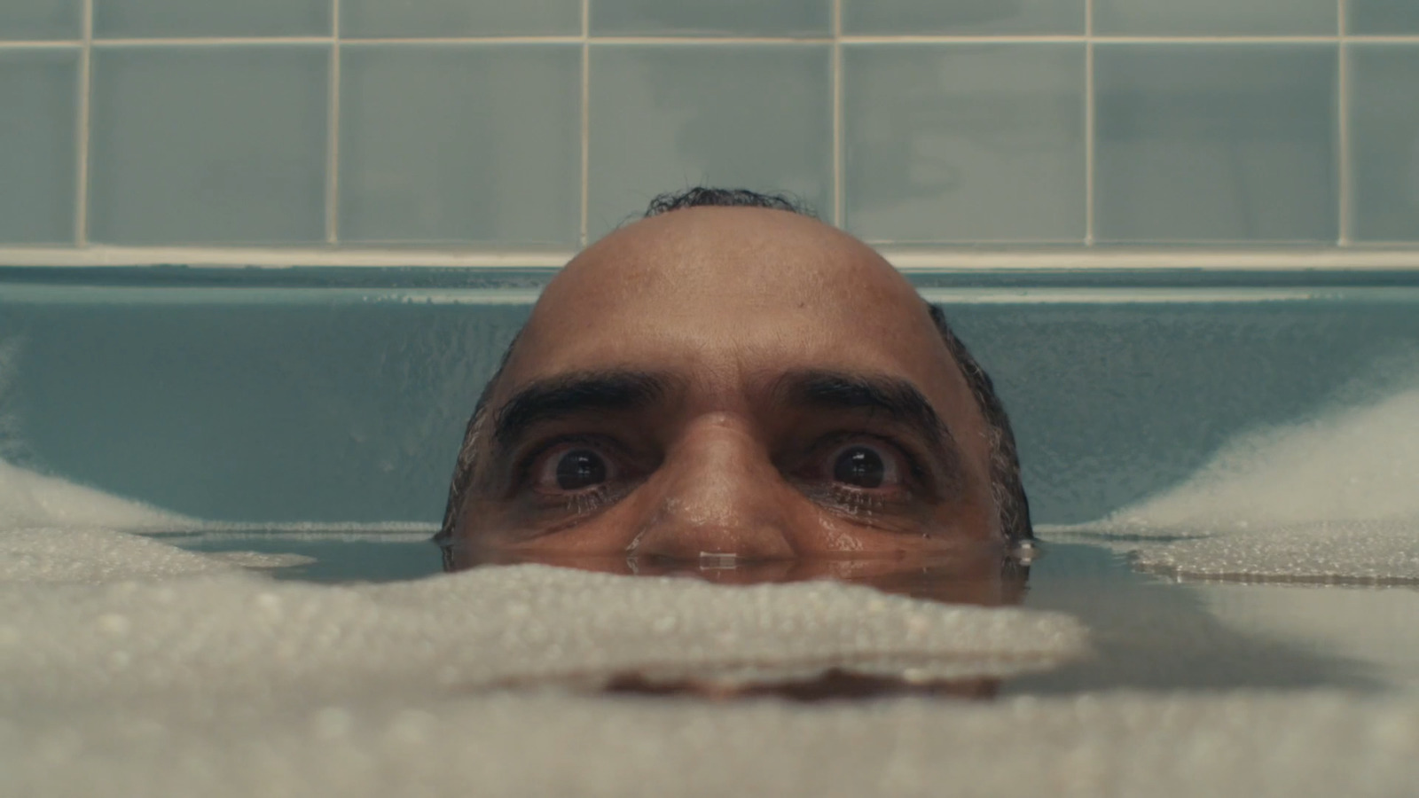 a man in a bathtub with a towel on his head