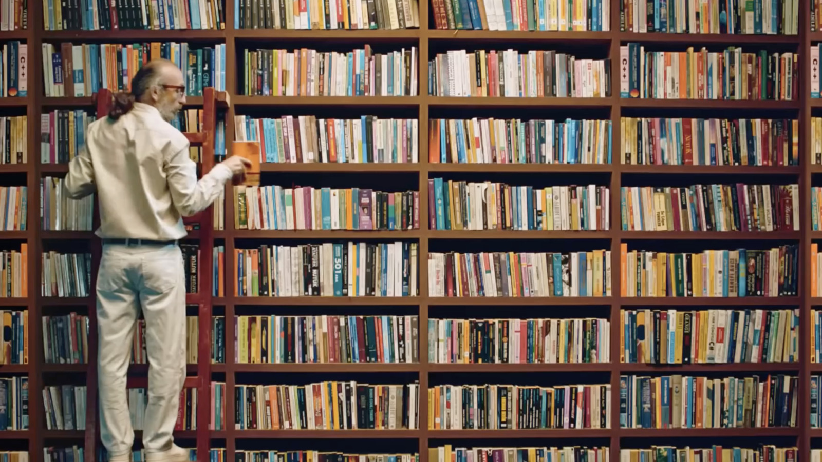 a man standing in front of a book shelf filled with books