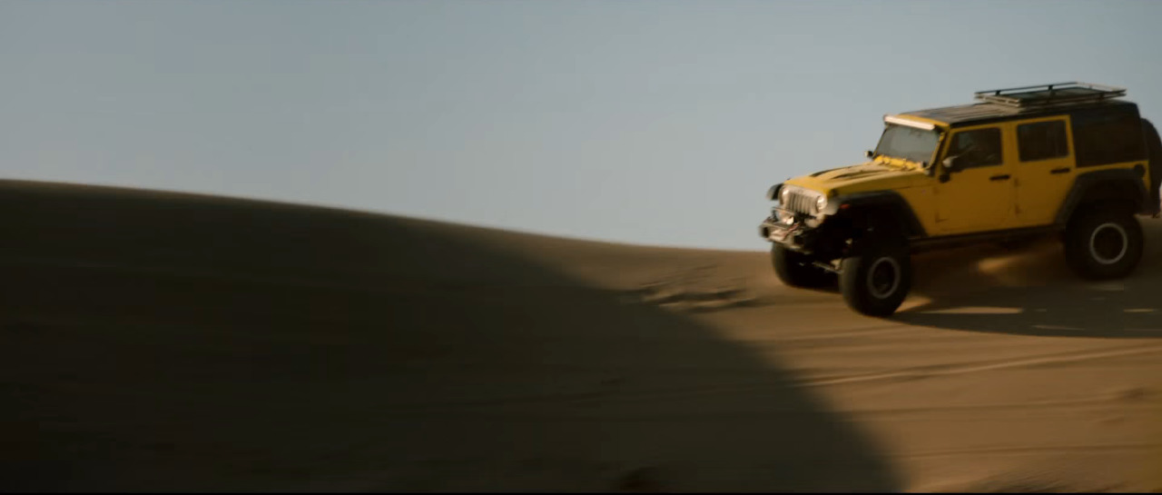 a yellow jeep driving through the desert