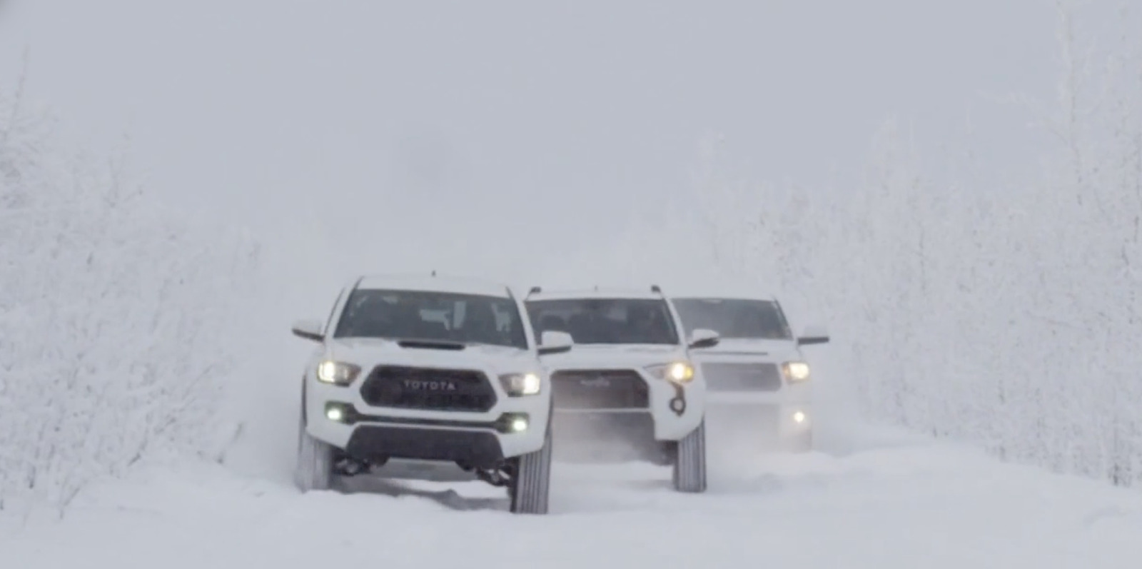 a couple of trucks driving down a snow covered road