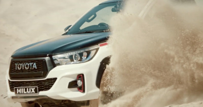 a white truck driving through a sandy area