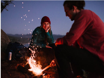 a man and a woman sitting around a campfire