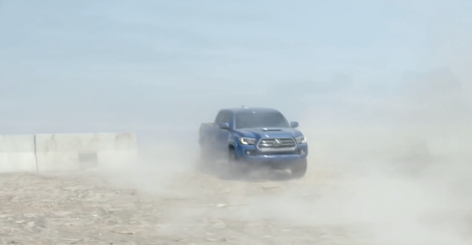 a blue truck driving down a dirt road