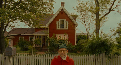 a man standing in front of a red house