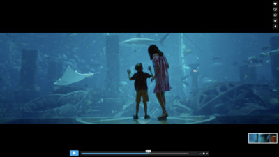 a woman and a child standing in front of a fish tank