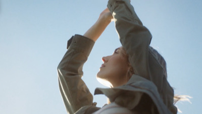 a woman reaching up into the air to catch a frisbee