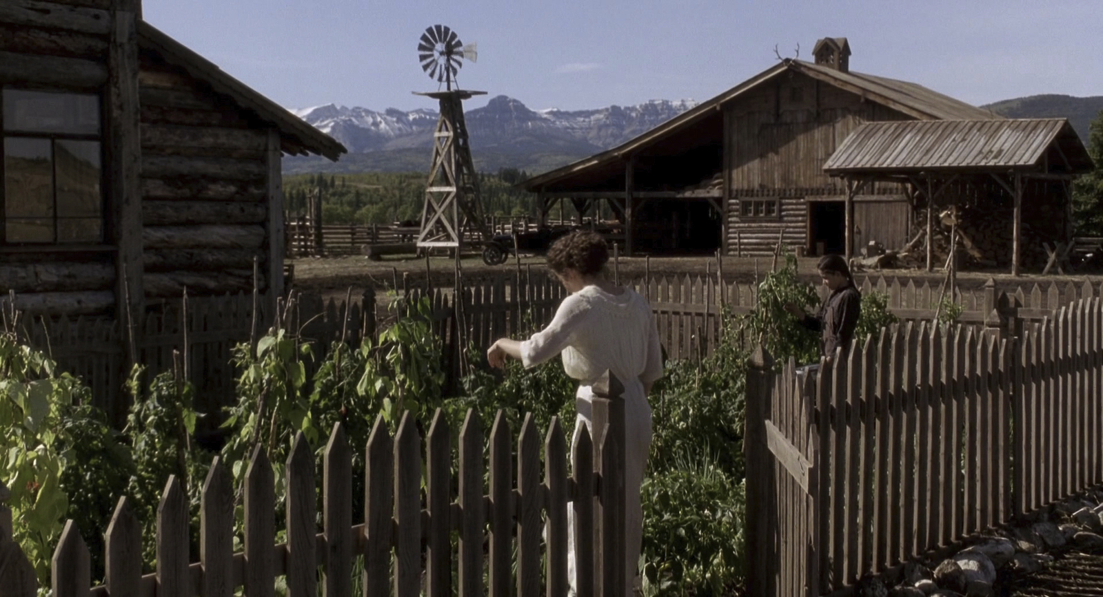 a woman standing next to a wooden fence