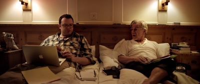 a couple of men sitting on top of a bed next to each other