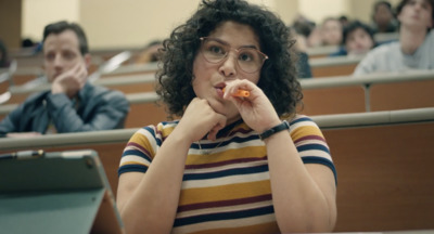 a woman sitting in a lecture hall eating a piece of food