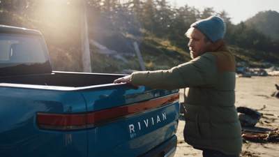 a woman standing next to a blue pickup truck