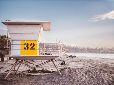 a lifeguard tower on the beach with a yellow sign on it