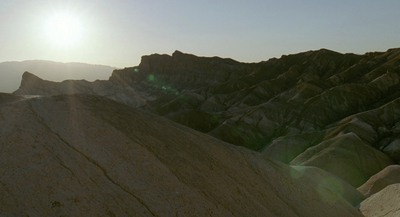 the sun is shining over a rocky mountain range