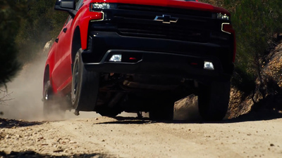 a red truck driving down a dirt road