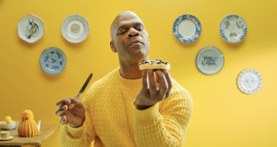 a man in a yellow sweater eating a piece of cake