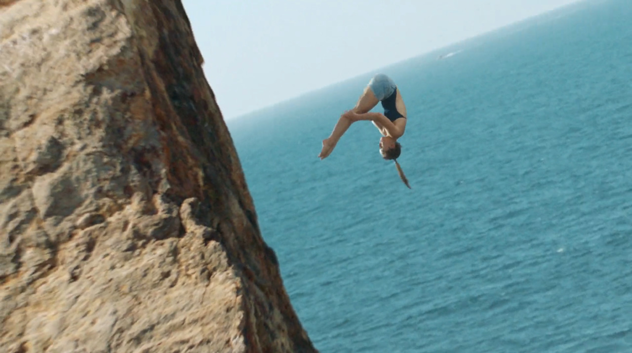 a person doing a handstand on a cliff above the ocean