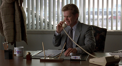 a man sitting at a desk talking on a phone