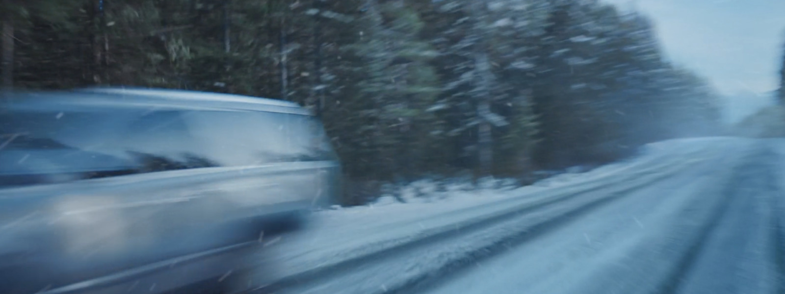 a blurry photo of a car driving down a snowy road