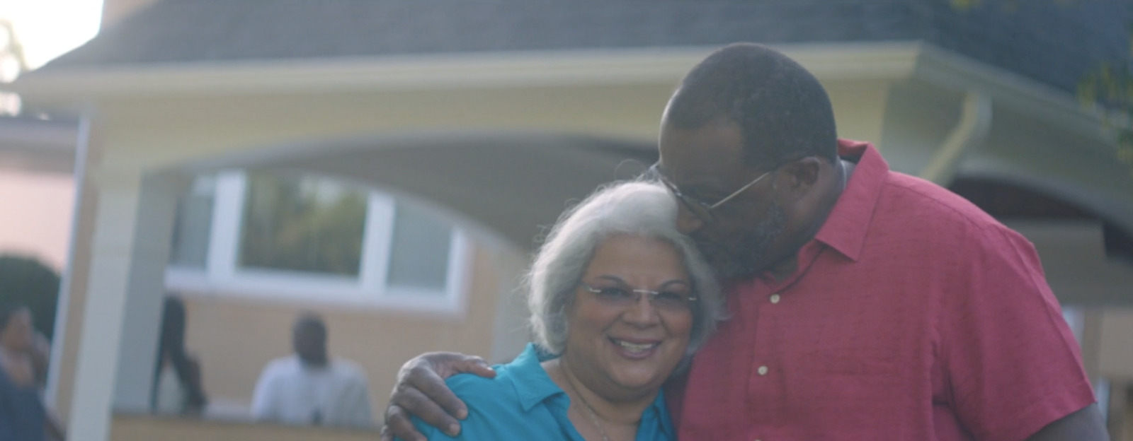 a man and a woman standing in front of a house