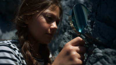 a young girl holding a magnifying glass up to her face