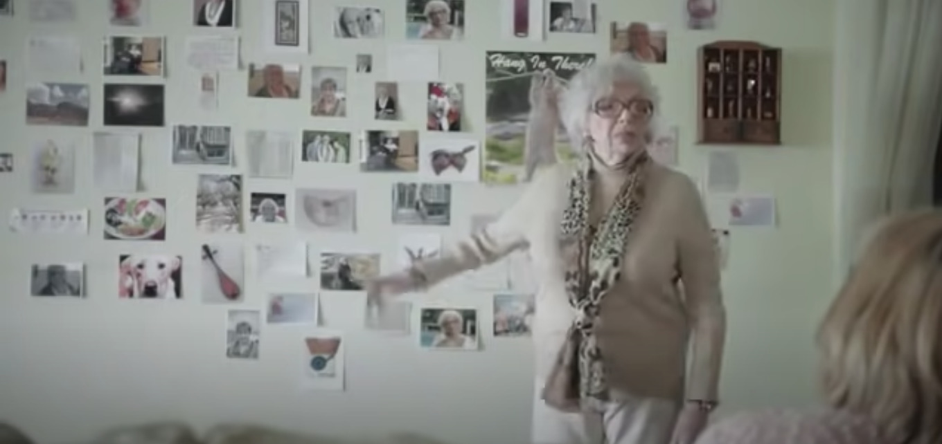 a woman standing in front of a wall with pictures on it