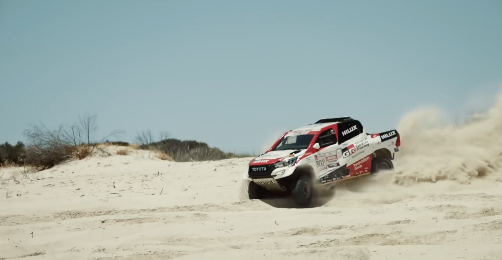 a red and white truck driving through the sand