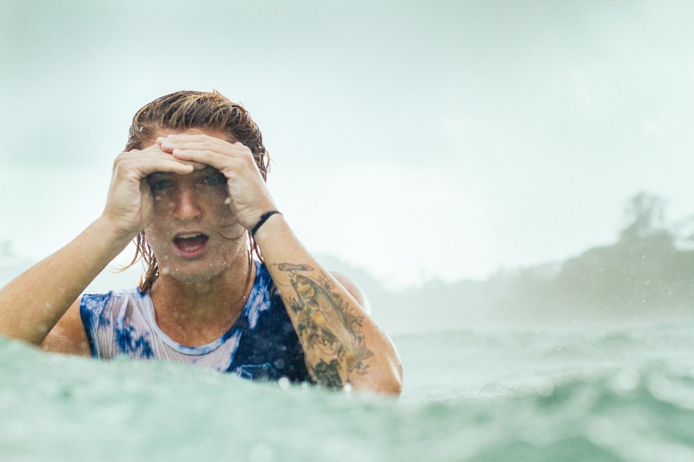 a man in the water covering his eyes with his hands