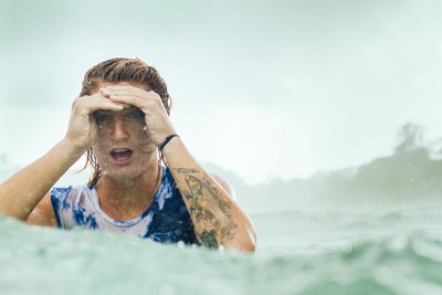 a man in the water covering his eyes with his hands