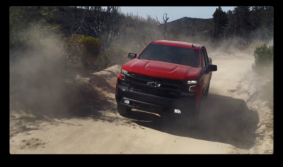 a red truck driving down a dirt road