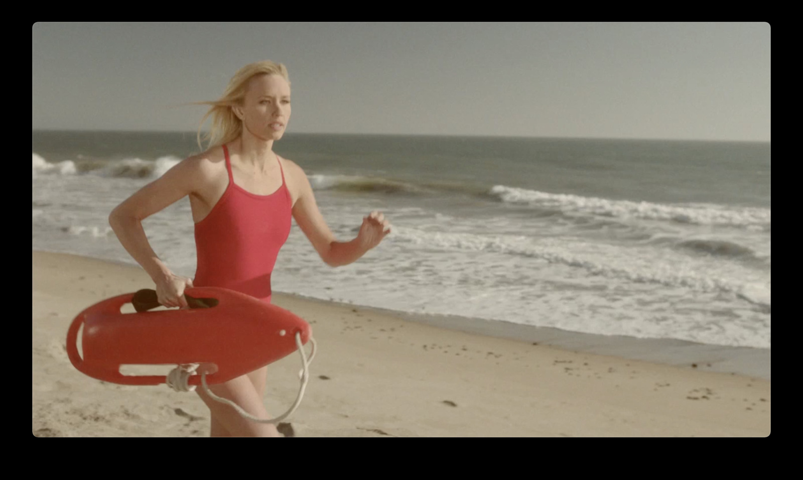 a woman running on the beach with a life preserver