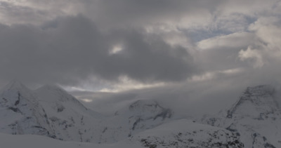 a snow covered mountain range under a cloudy sky