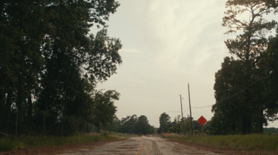 a dirt road with a stop sign on the side of it