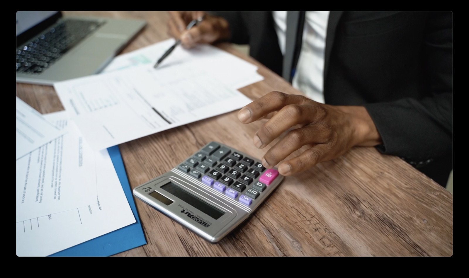 a person sitting at a desk with a calculator