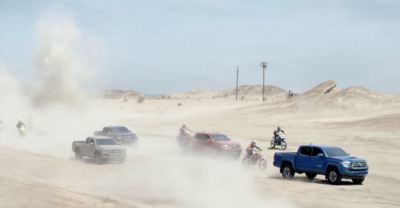 a group of trucks driving down a dirt road