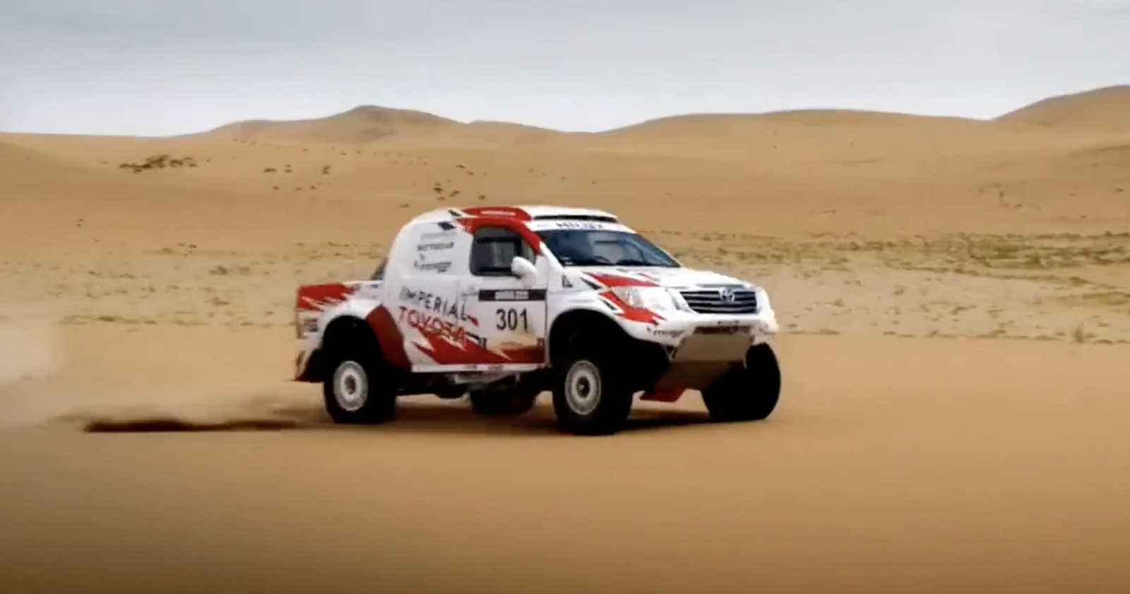 a white truck driving through a sandy desert