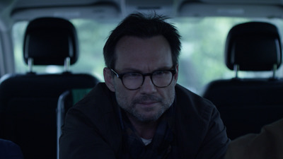 a man wearing glasses sitting in the back of a van