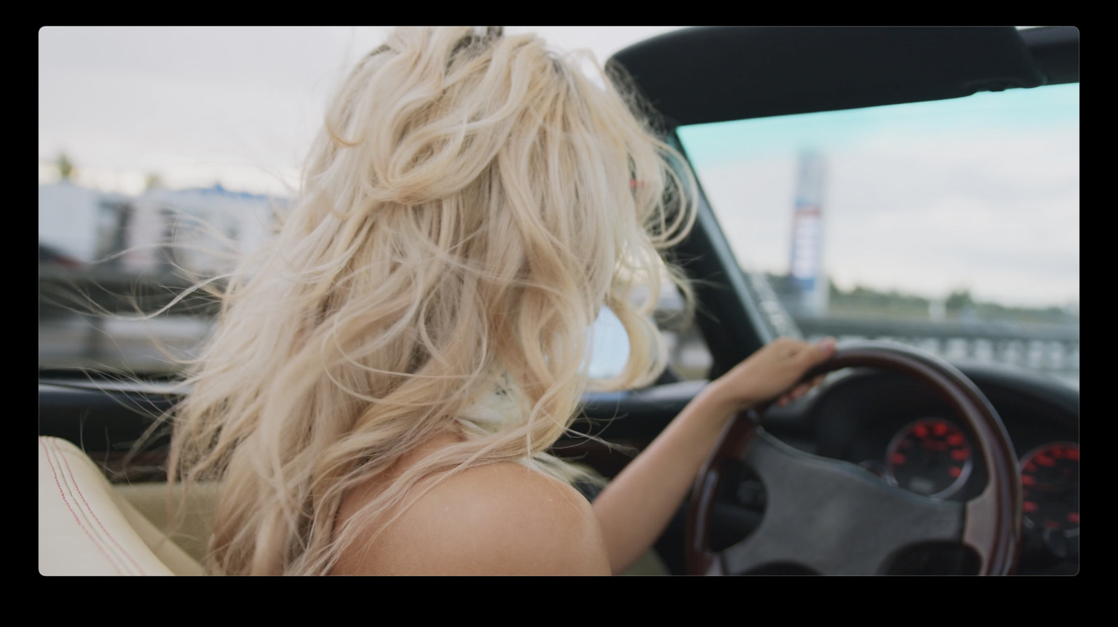 a blonde woman driving a car down a street